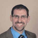 Profile photo of Pastor Jim Larger. He is wearing a brown suit and looking into camera.