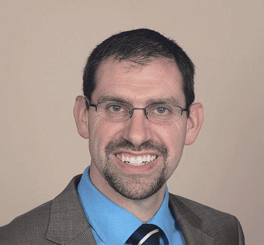 Profile photo of Pastor Jim Larger. He is wearing a brown suit and looking into camera.