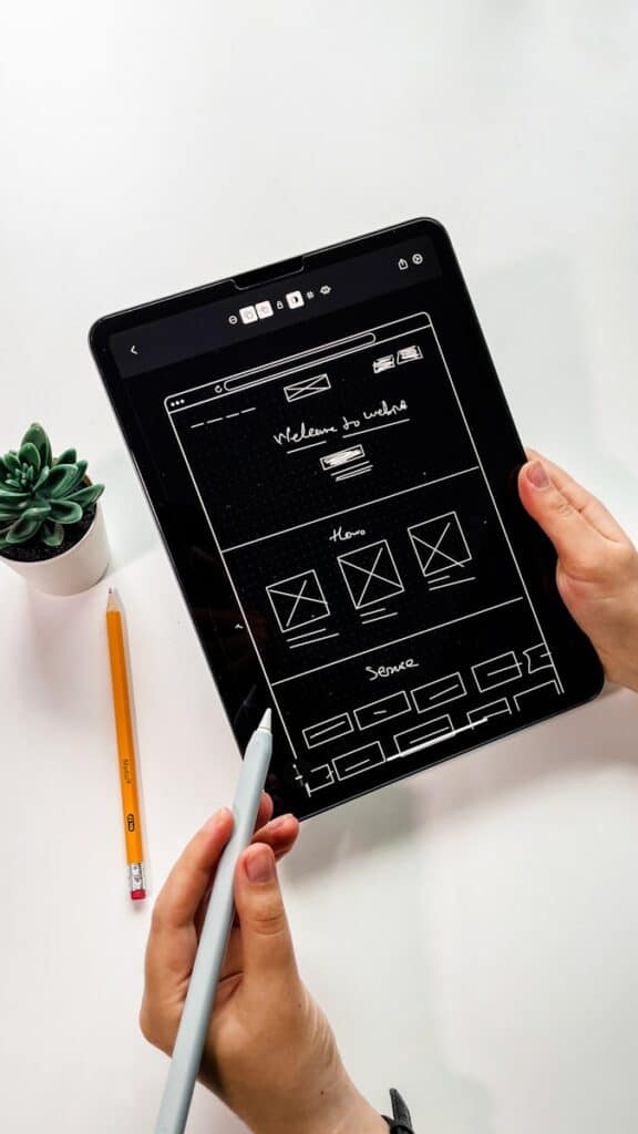 person holding black ipad showing hand drawn wireframes