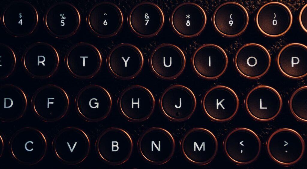 A close up of a black keyboard with round keys. The keys have a orange glow around them.