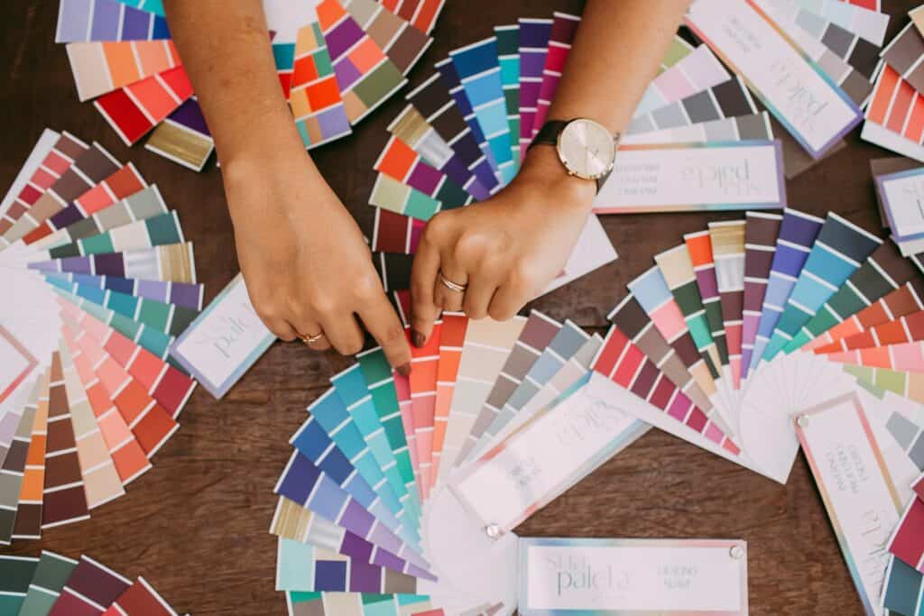 several color swatches laying out on a table with a woman's hands grabbing one.