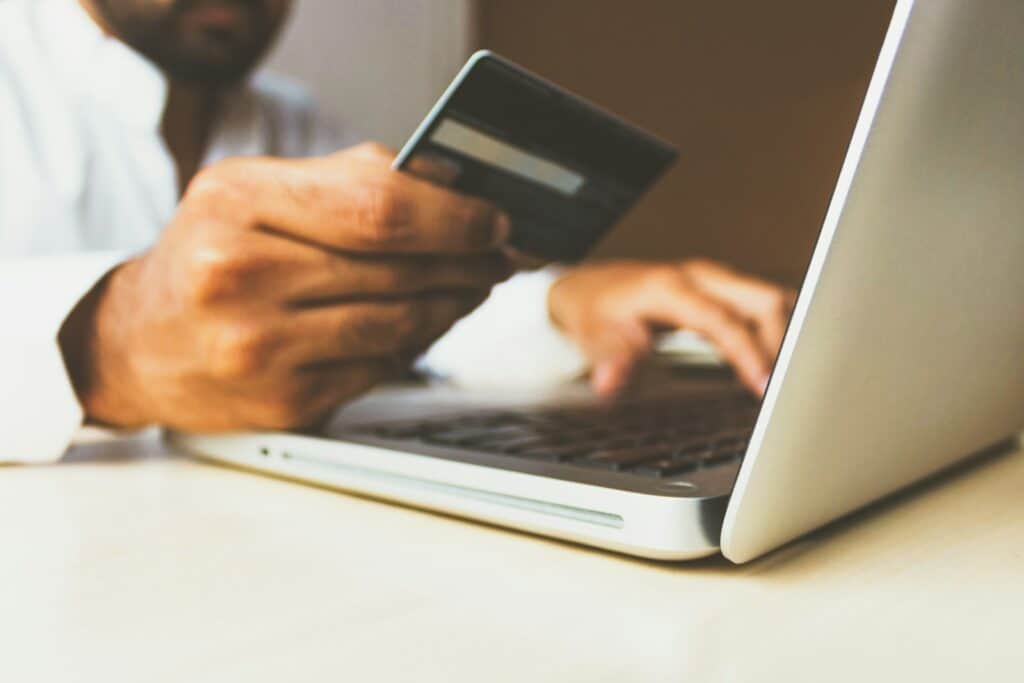 Person using a laptop while holding a credit card: online shopping